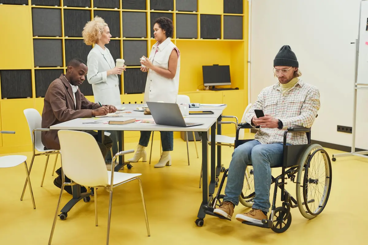 Equipe diversa em ambiente de escritório, incluindo profissional em cadeira de rodas